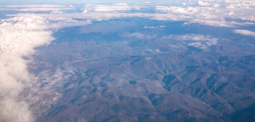 a bird's-eye view of the mountains and clouds in the sky from an airplane window