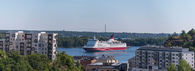 Panorama view a cruise ship from Finland passing the bay Saltsjön with water front apartment houses, a sunny summer day in Stockholm 