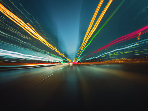 Beautiful image of colorful light trails from fast night drive on the highway, front view from the car window.
