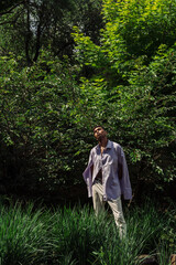 fashionable african american man posing with closed eyes in summer park