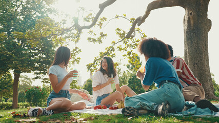 Happy smiling young multinational people at picnic on summer day outdoors. Friends have fun weekend...