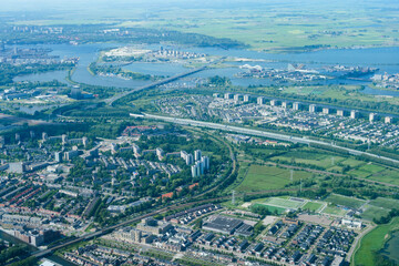 Obraz premium Aerial view from airplane of modern city with buildings, skyscrapers and highways between river. Amsterdam, Holland 