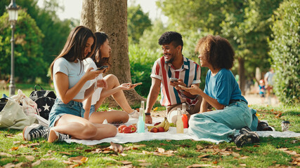 Close-up of young man with curly hair wearing striped shirt sitting in park having picnic on summer...