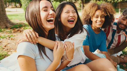 Happy multiethnic young people posing for the camera at picnic on summer day outdoors. Group of friends looking at the camera and laughing merrily