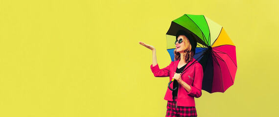 Fototapeta premium Autumn portrait of happy smiling young woman holding colorful umbrella wearing jacket on background