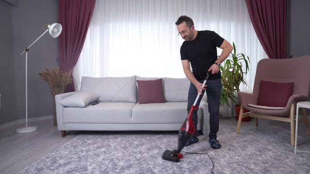 The man is cleaning the house.
Man using vacuum cleaner and cleaning house.
