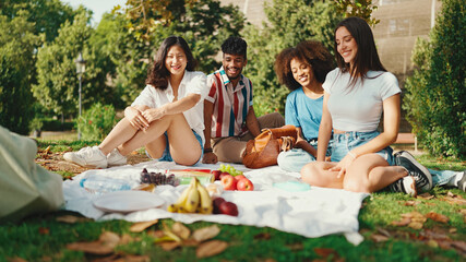 Happy smiling young multinational people at picnic on summer day outdoors. Friends have fun weekend...