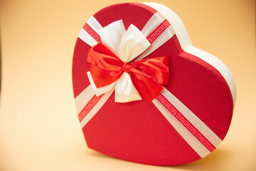A shiny red love heart gift box with red ribbon