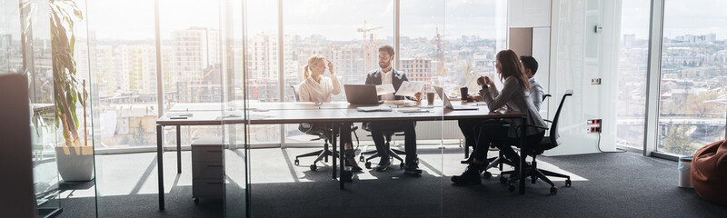 Team of businessmen communicating together after meeting in office with panoramic windows.