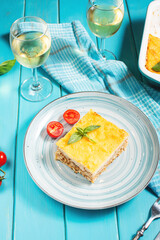 Delicious homemade italian Lasagna with bachamel sauce and glasses of wine on wooden background