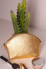 Fototapeta na wymiar golden leather cosmetic bag with brush closeup photo on white wall background
