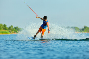 Fototapeta premium A professional wakeboarder rides on the lake in sunny weather, performing figures