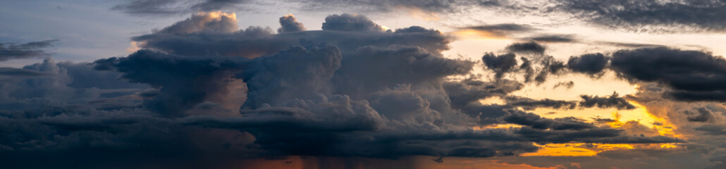 Panorama sunset sky and dark clouds.Fluffy cloud in the black sky background.Vivid sky on dark cloud before summer storm.