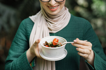 Close up view of hand of woman having a vegetables salad for lunch, healthy eating standing on...