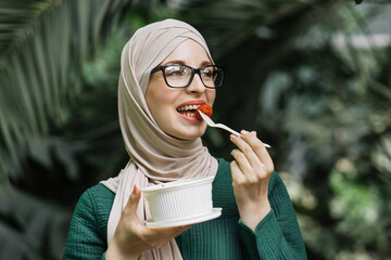 Portrait of smiling muslim business woman eating healthy salad while having break during work. Kind...