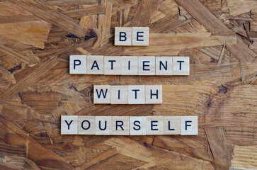 be patient with yourself text on wooden square, motivation quotes