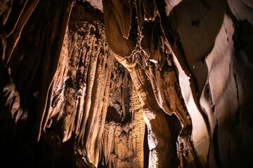 Low-angle view of long mineral stalactites hanging from the ceiling of the cave