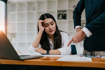 Furious boss scolding young frustrated interns. Ineffective office workers sitting at the table and...