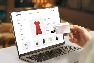 Shopping online with credit card concept. Modern e-commerce web page with woman clothes on laptop display - obrazy, fototapety, plakaty