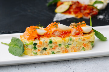Shaped in a form salad topped with caviar and quail eggs. Spinach on sides.