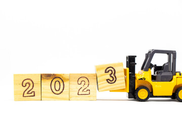Toy forklift hold letter block 3 to complete word 2023 on wood background