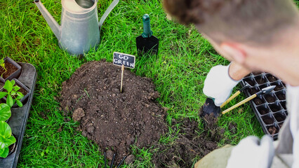 Blurred gardener holding shovel near soil and board with go green lettering in garden