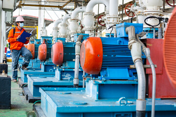 Male worker inspection pump motor oil at steel long pipes and pipe elbow in station oil factory...