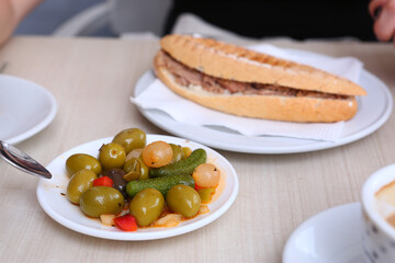 breakfast in open air summer cafe with tuna sandwich, cup of coffee, olives, cucumber and onion close up photo