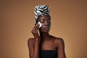 Elegant black girl wipe her face with cotton swab