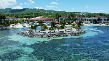 Aerial of hotels on a beach covered with greenery against a turquoise sea in Montego Bay, Jamaica - obrazy, fototapety, plakaty