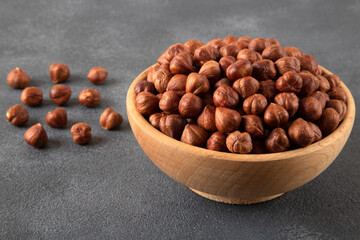 Top view of a bowl full of hazelnuts on dark background