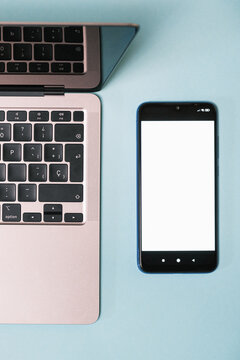 Top view of a smartphone with blank screen close to a laptop on desktop