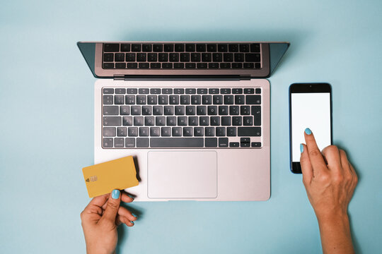 Top view of anonymous hand using mobile phone   while making an online payment with a credit card and a laptop 