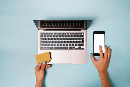 Top view of anonymous hand using mobile phone   while making an online payment with a credit card and a laptop 