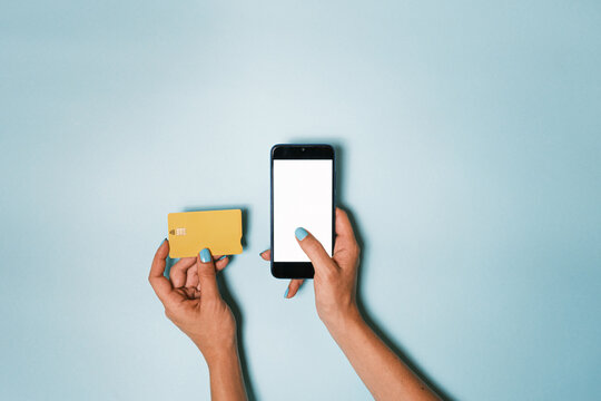 Hand scrolling a smartphone with blank screen while other hand holding a bank credit card