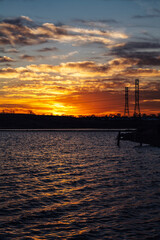 Fototapeta premium High voltage electricity tower sky sunset landscape, industrial background with water lake on front. High-quality photo