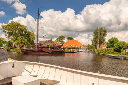White sloop in front of an old sailing boat in a canal in the Dutch village of Heeg, Friesland, The Netherlands