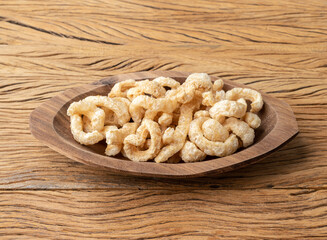 Fried pork skin cracklings on a plate over wooden table