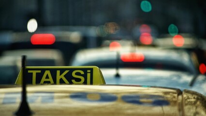 Taxi sign on the top of the yellow car against a blurred background,
translation: taxi
