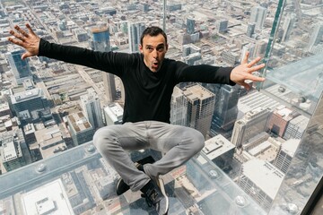 Hispanic man sitting in the high Willi Tower in Chicago city and opening his arms