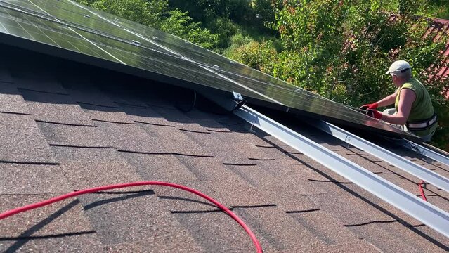 Worker prepare and cleans roof for installation of PV solar panels on bituminous tiles roof