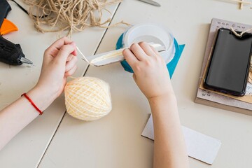 Work of young designer in action. Winding colored thread on paper template. There is telephone