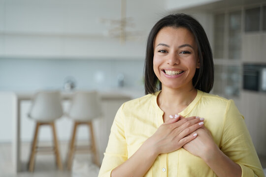 Grateful smiling woman hold hands on chest feels gratitude, appreciates help, good deed at home