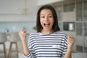 Excited happy woman makes yes gesture, celebrates relocation at new house, achievement, success