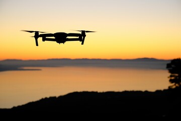 Closeup of the silhouette of a drone against the sunset background