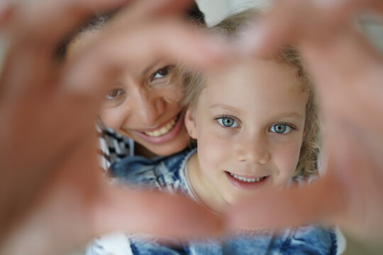 Adopted daughter, mother make heart gesture, symbol of child love care support. Motherhood, adoption