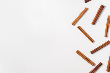 An arrangement of many short cinnamon sticks arranged randomly to the right in a flat lay. Culinary concept in a minimalistic style from spices for making drinks and baking. Top view with copy space.
