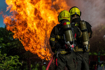 firefighters wearing fire fighter suit for safety and using twirl water extinguisher for fighting...