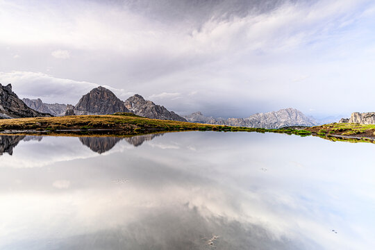 Bright sky at dawn over Monte Cristallo and Tofane mountains mirrored in water, Giau Pass, Dolomites, Veneto, Italy