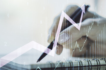 Double exposure of abstract creative financial diagram with upward arrow and woman hand writing in notepad on background, growth and development concept